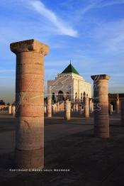 Image du Maroc Professionnelle de  Le tombeau du plus populaire des sultans du Maroc, Mohammed V, père de l’indépendance repose ici dans cette  demeure bâtie en marbre blanc et couronnée par un toit pyramidale orna de tuiles vertes, symbole de la royauté. Sa construction a nécessita une dizaine d’année, au premier plan  les colonnes de l’esplanade de la Mosquée Hassan à Rabat, Jeudi 1er Mars 2007. (Photo / Abdeljalil Bounhar)
